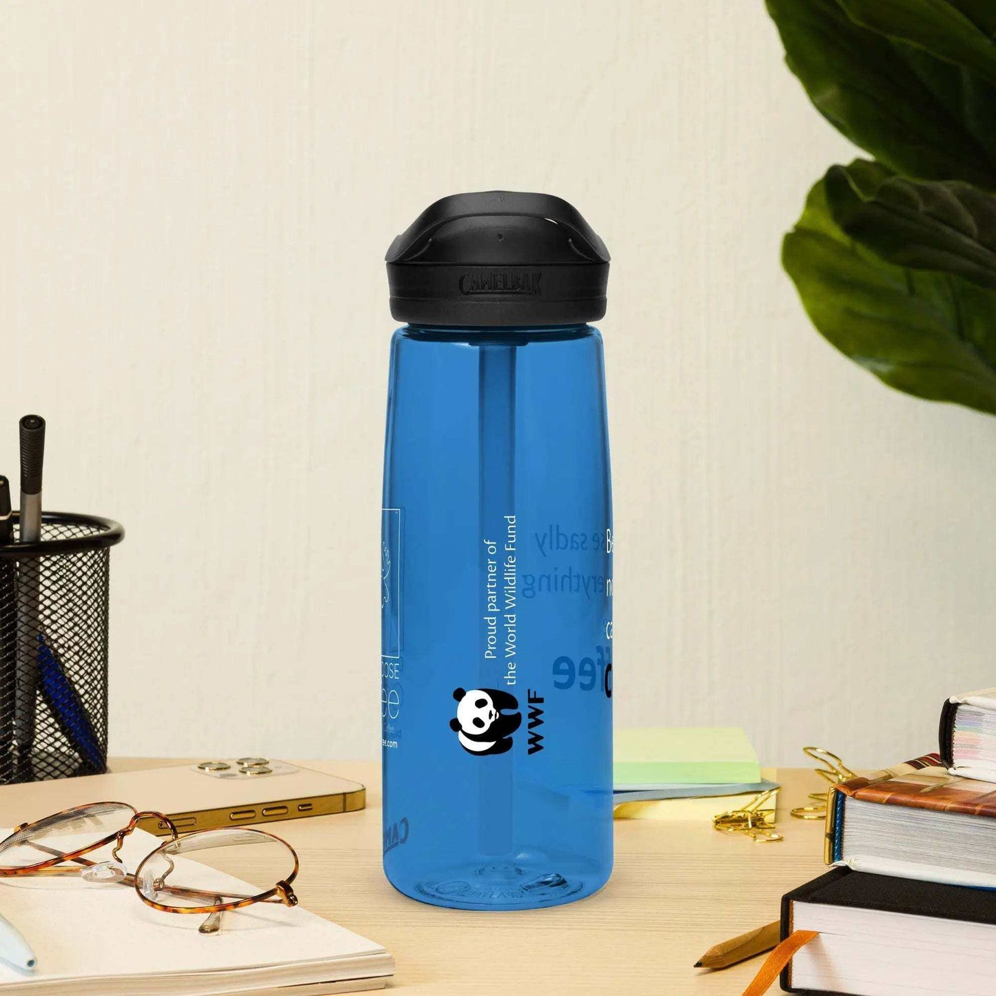 Blue CamelBak Eddy+ Water Bottle made from 50% recycled plastic with spill-proof lid and bite valve on desk next to glasses and books